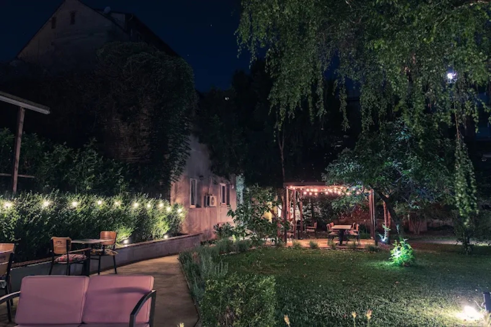 Dvorište s lampicama i pergolom noću